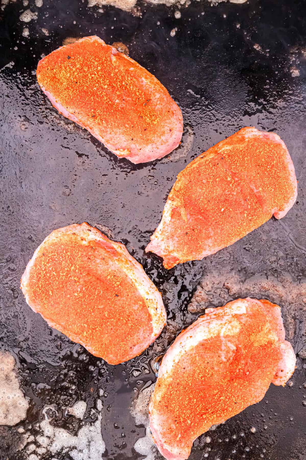 Seasoned pork chops on griddle for Blackstone Pork Chops