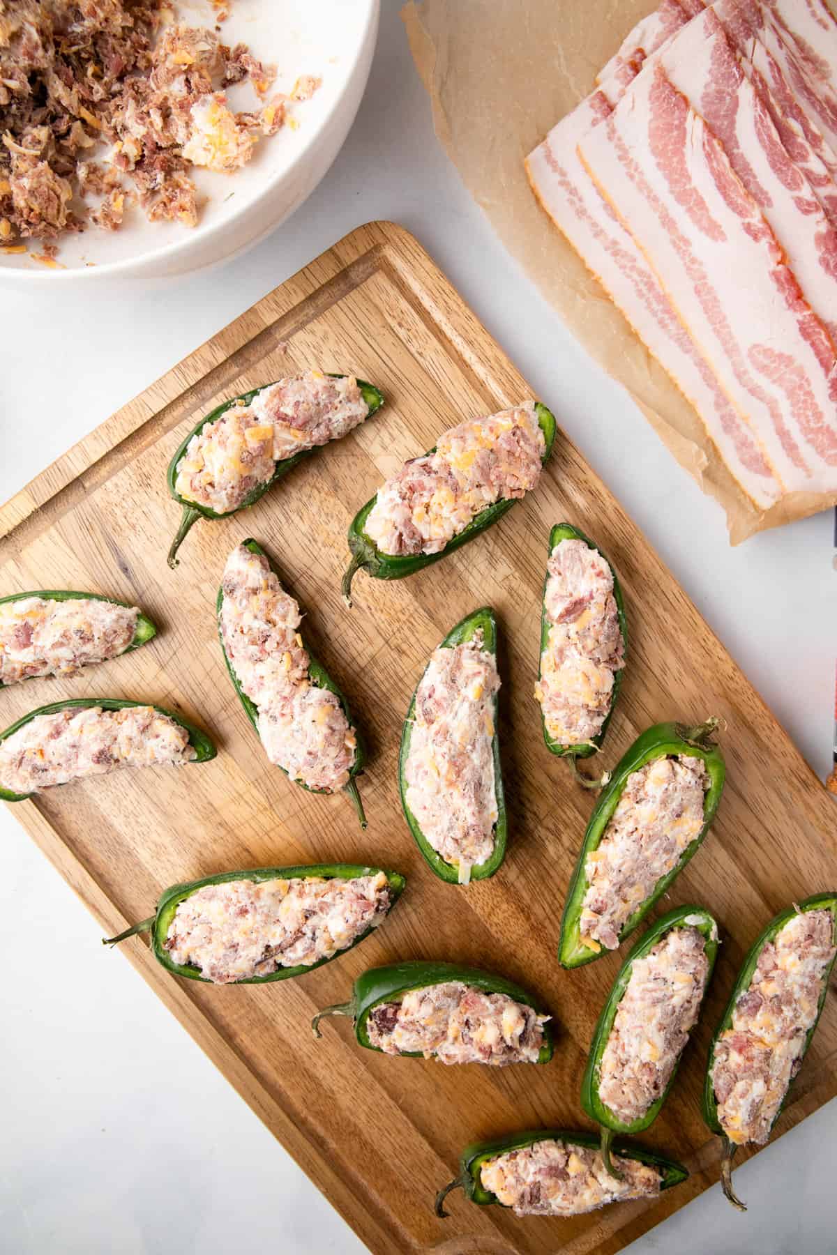 Sliced jalepenos filled with mixed stuffing arranged on cutting board