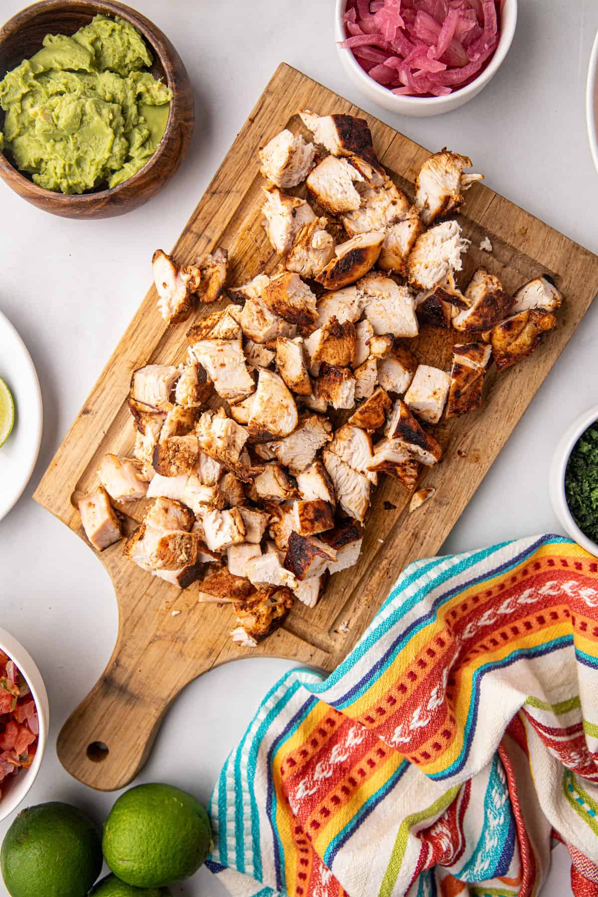 Cooked and diced chicken breasts on wooden cutting board for Chicken Street Tacos