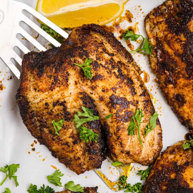 Spatula lifting blackened fish off a serving platter