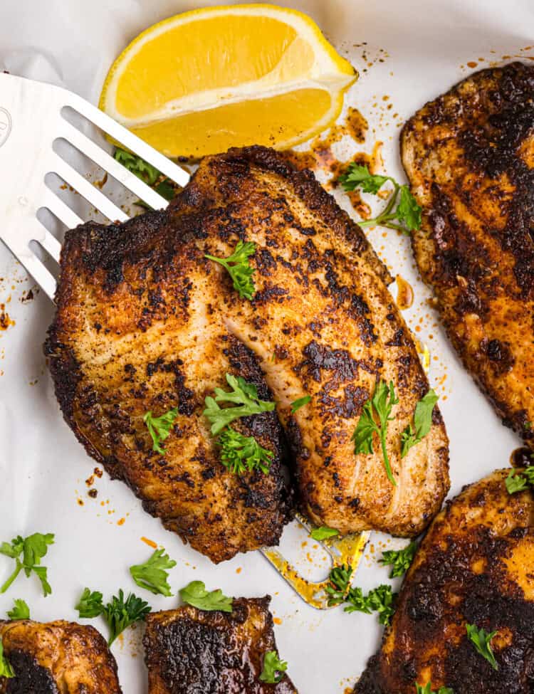 Spatula lifting blackened fish off a serving platter