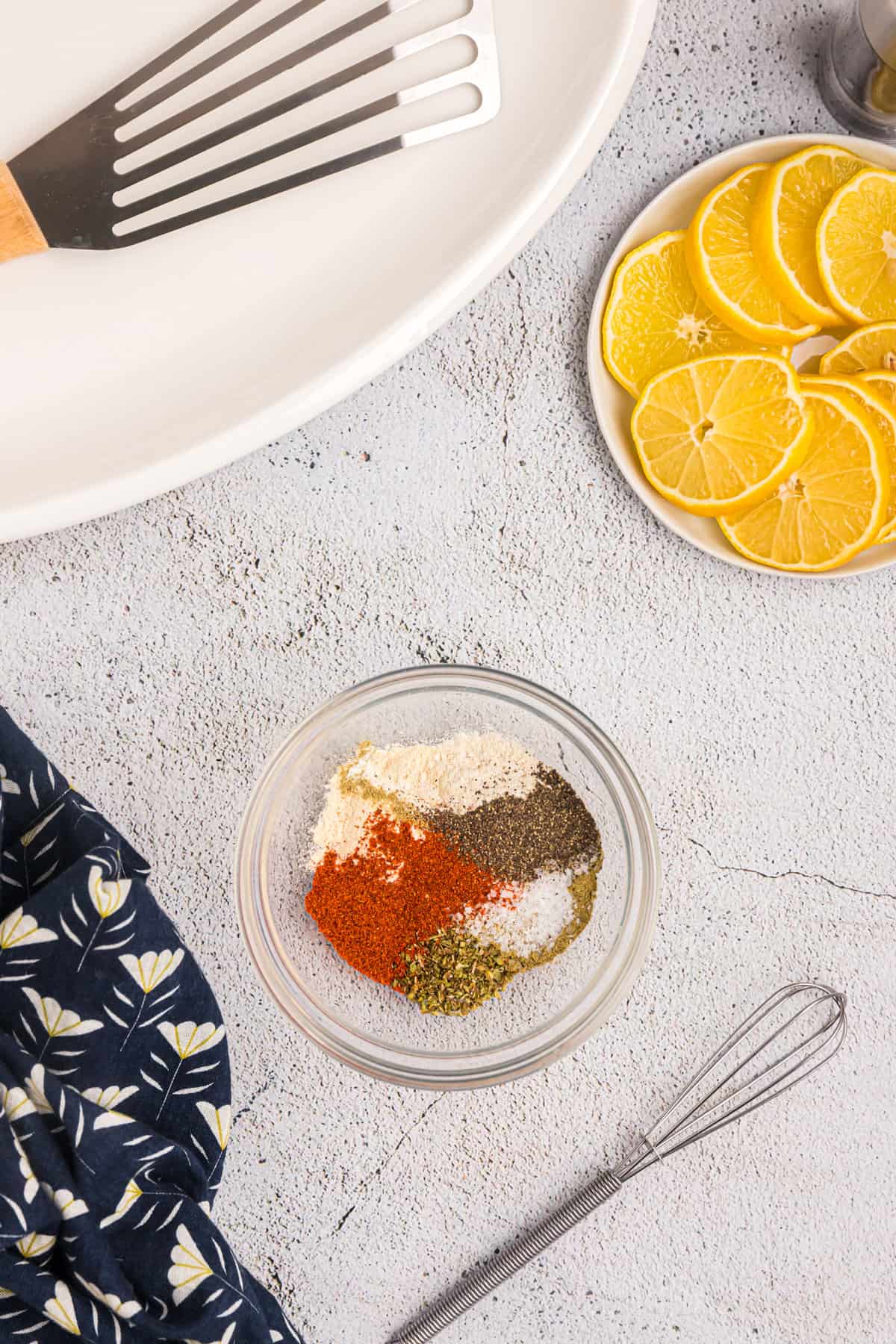 Spices and ingredients for Blackened Seasoning recipe in shallow mixing bowl with small whisk