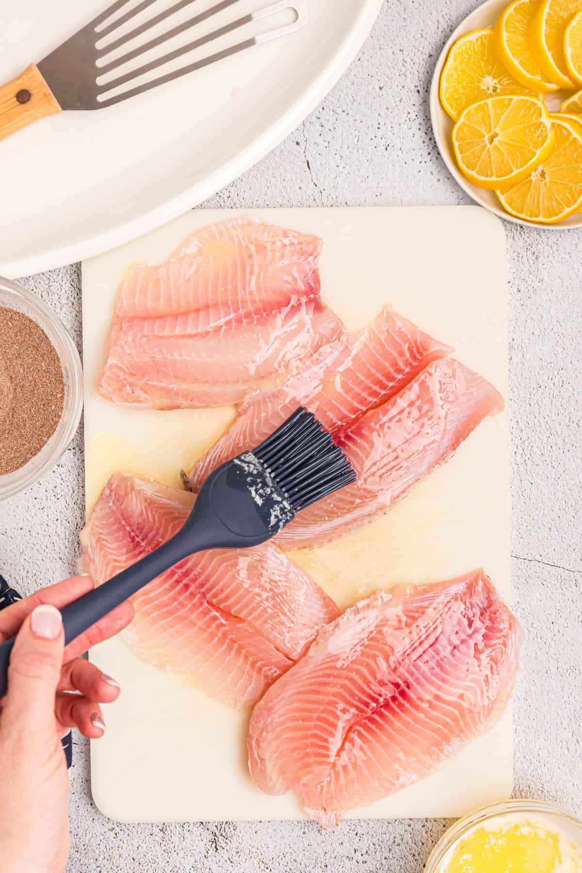 Smothering fish fillets with butter prior to seasoning for Blackstone Blackened Fish recipe