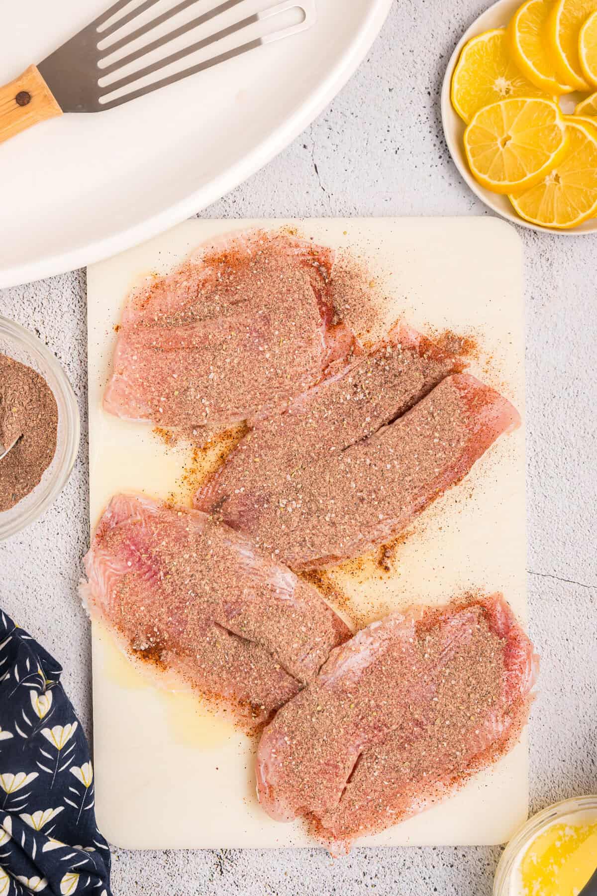Generously coating the buttered fish fillets with blackened seasoning for Blackstone Blackened Fish recipe
