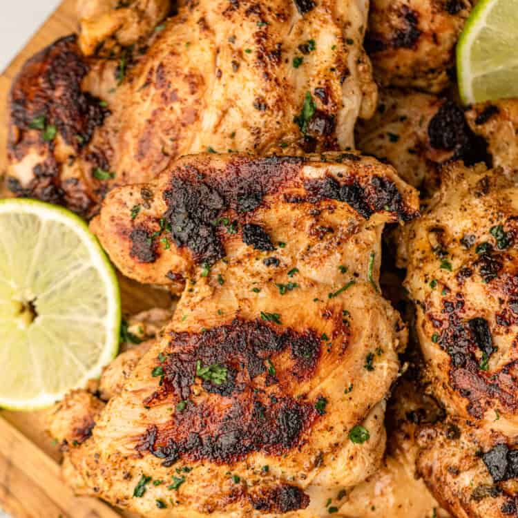Pollo Asado pieces arranged on wood cutting board with lemon and lime slices