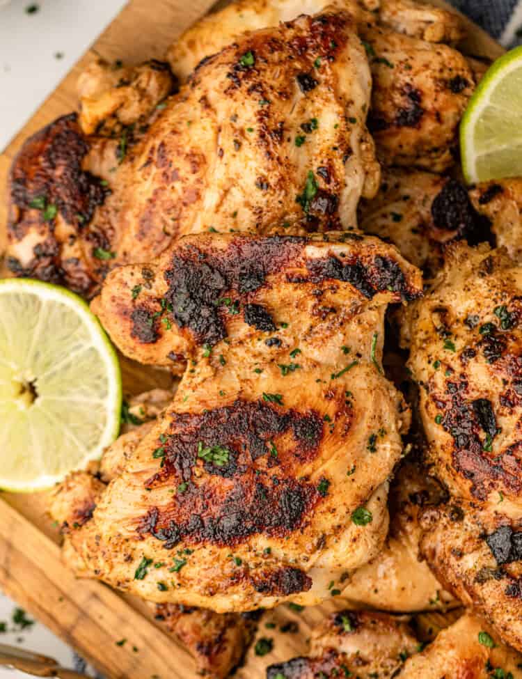 Pollo Asado pieces arranged on wood cutting board with lemon and lime slices