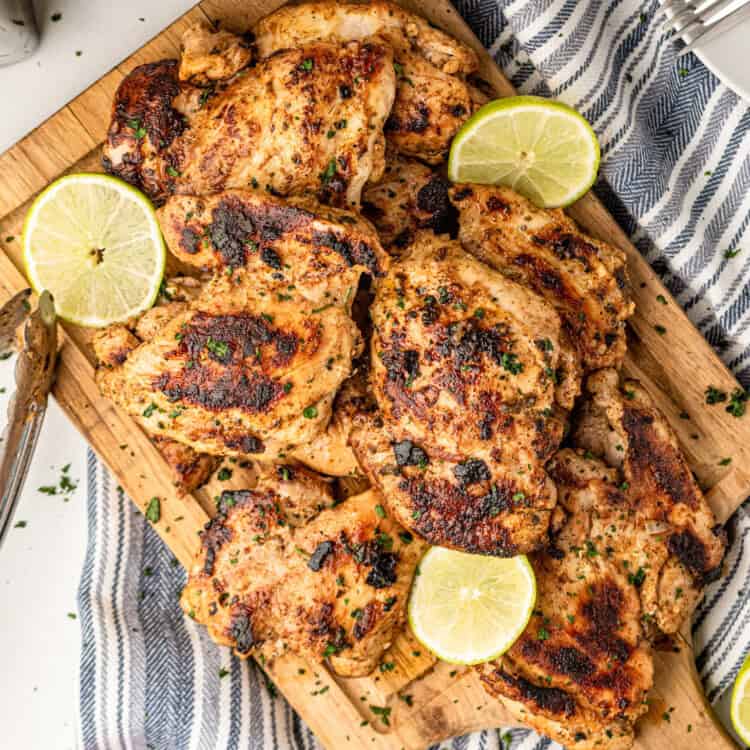 Pollo Asado on wooden cutting board with lemon and lime slices