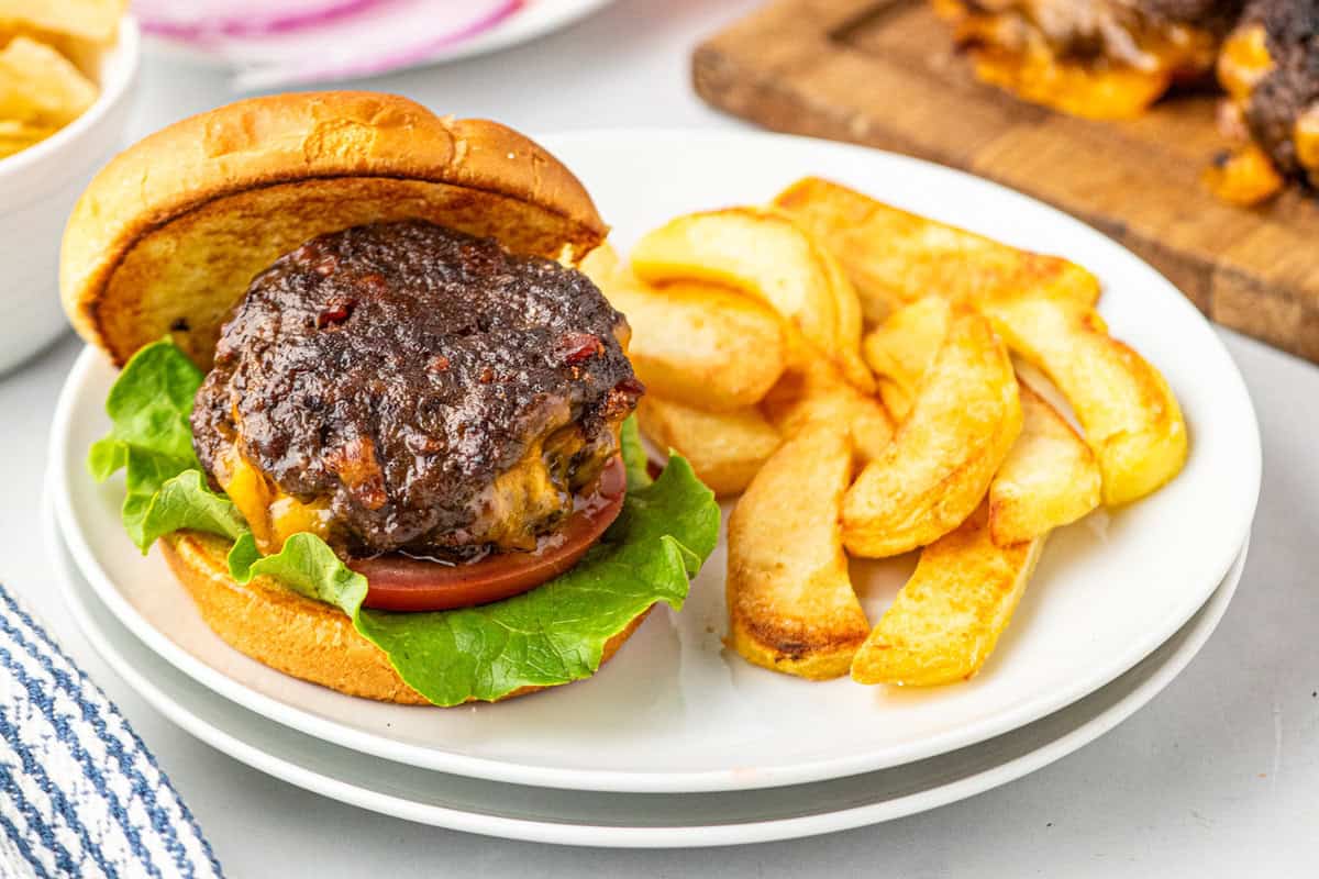 Stuffed Bacon Cheeseburger on toasted slice bun on plate with fries