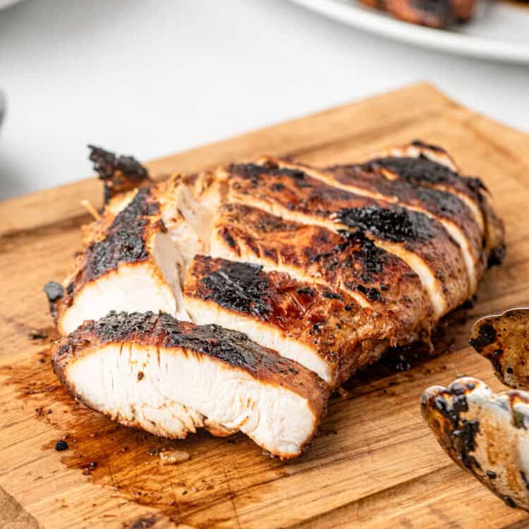 Closeup square image of Chicken Marinade on chicken breast sliced on wooden cutting board