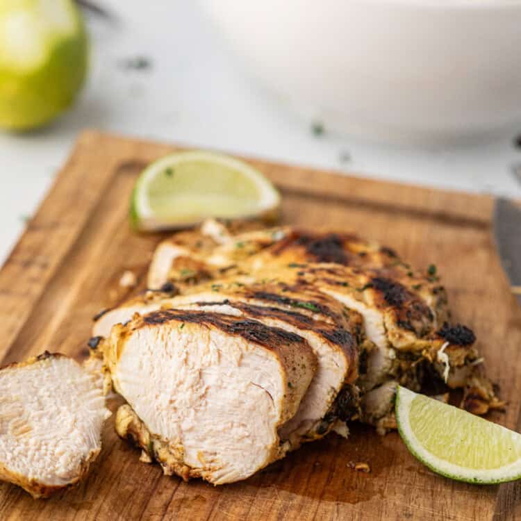 Grilled Cilantro Lime Chicken sliced with fresh lime slices on serving board