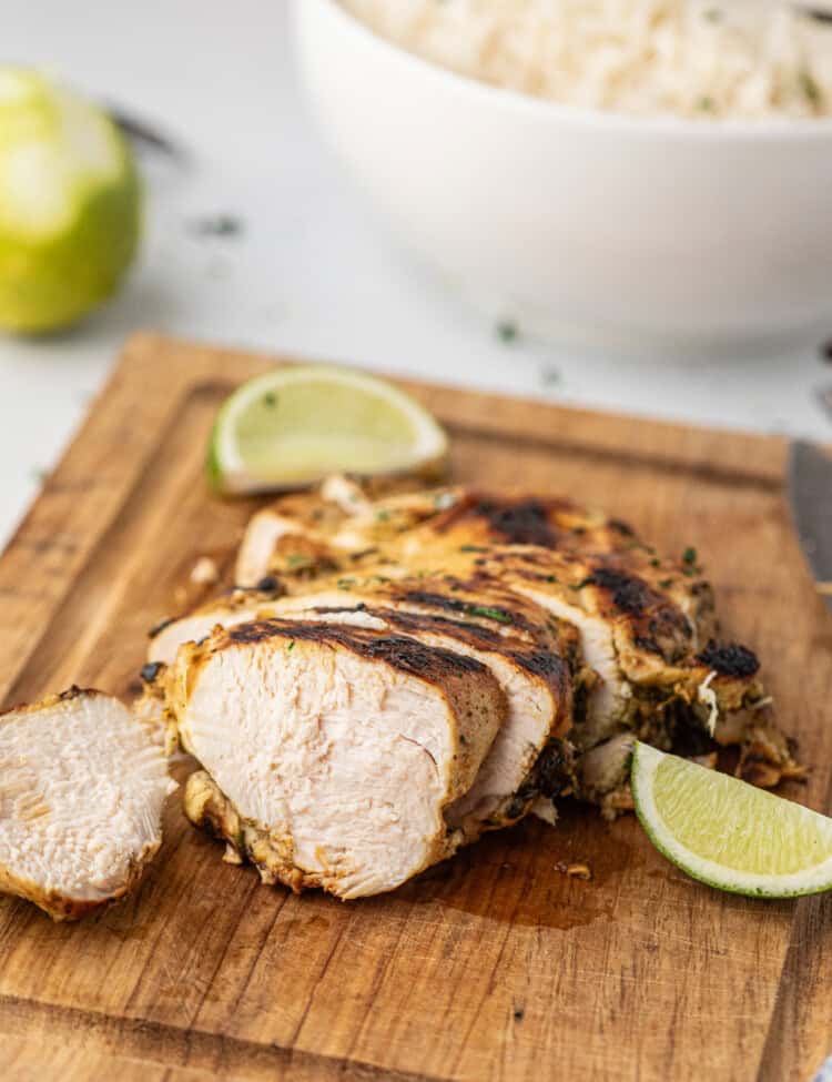 Grilled Cilantro Lime Chicken sliced with fresh lime slices on serving board