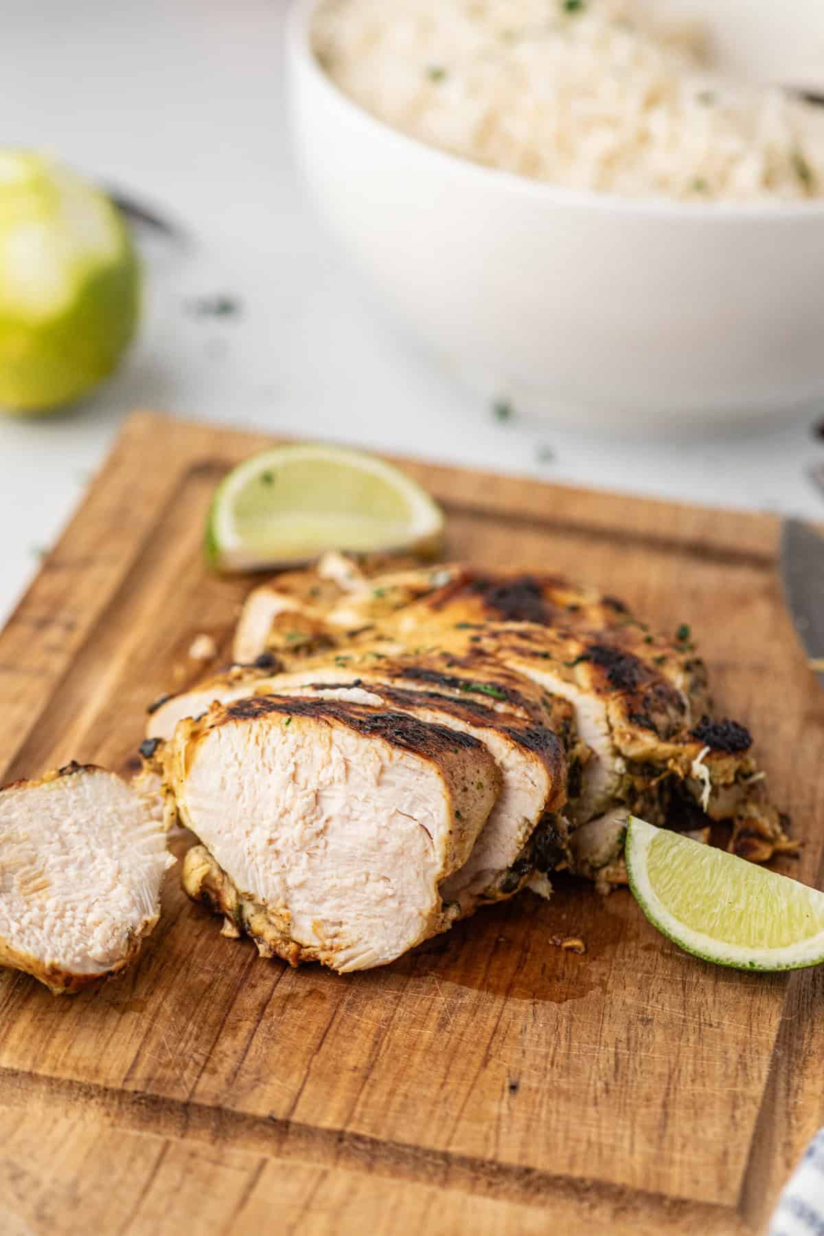 Grilled Cilantro Lime Chicken sliced with fresh lime slices on serving board