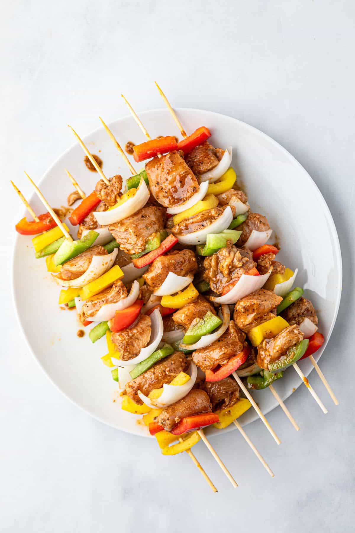 Assembled kabobs on wooden skewers stacked on plate for Chicken Fajita Kabobs recipe