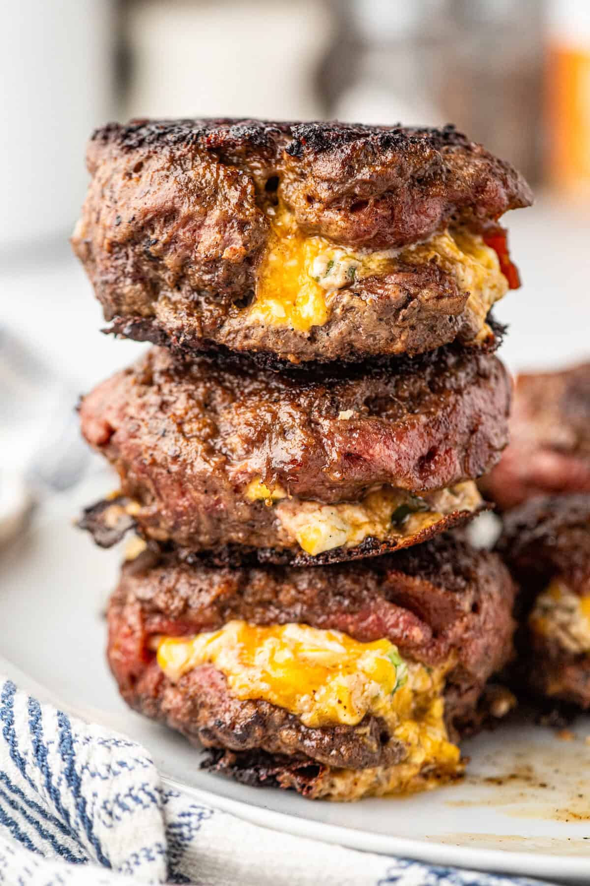 Jalapeno Popper Stuffed Burgers stacked on serving plate