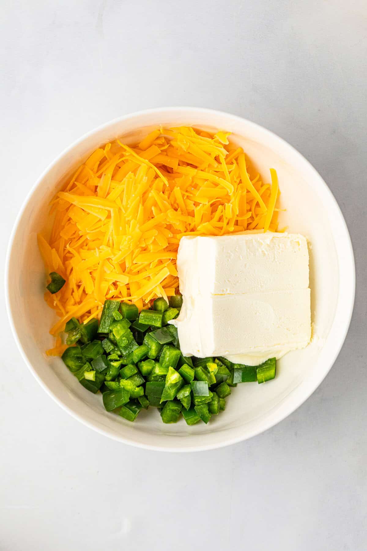 Cheeses and jalapenos in small mixing bowl for Jalapeno Popper Stuffed Burger recipe