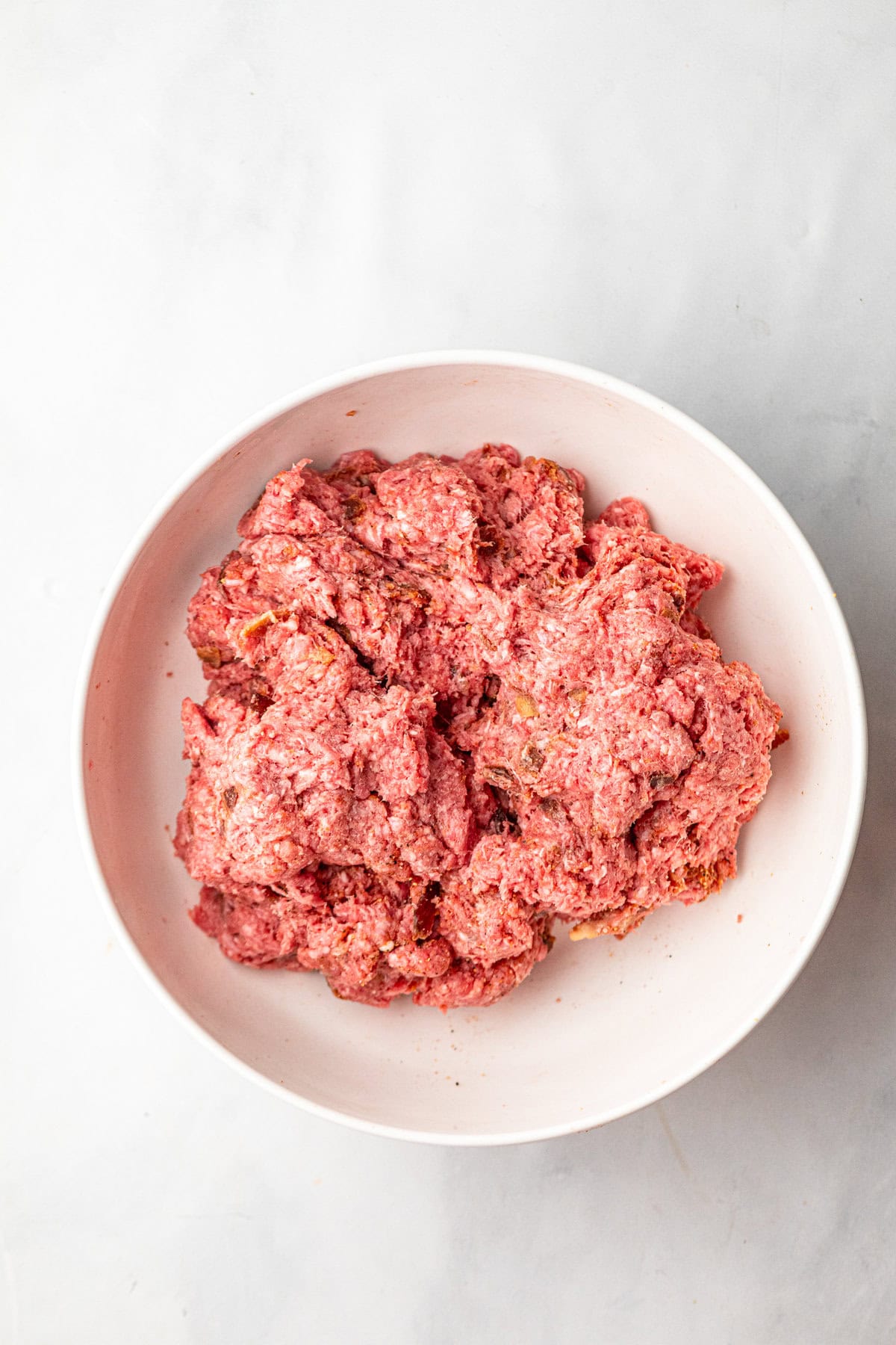 Seasoned ground beef in white mixing bowl for Jalapeno Popper Stuffed Burger