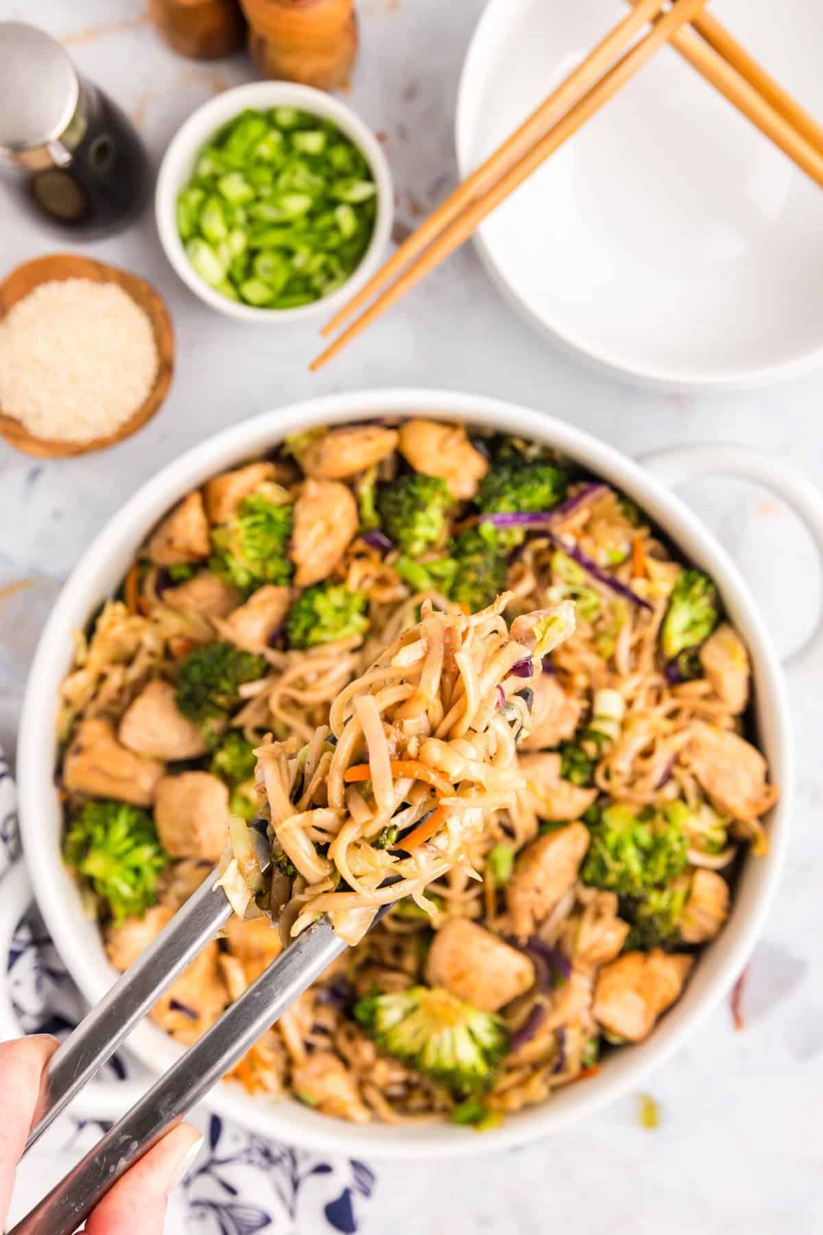 Blackstone Chicken Stir Fry in shallow serving bowl with tongs