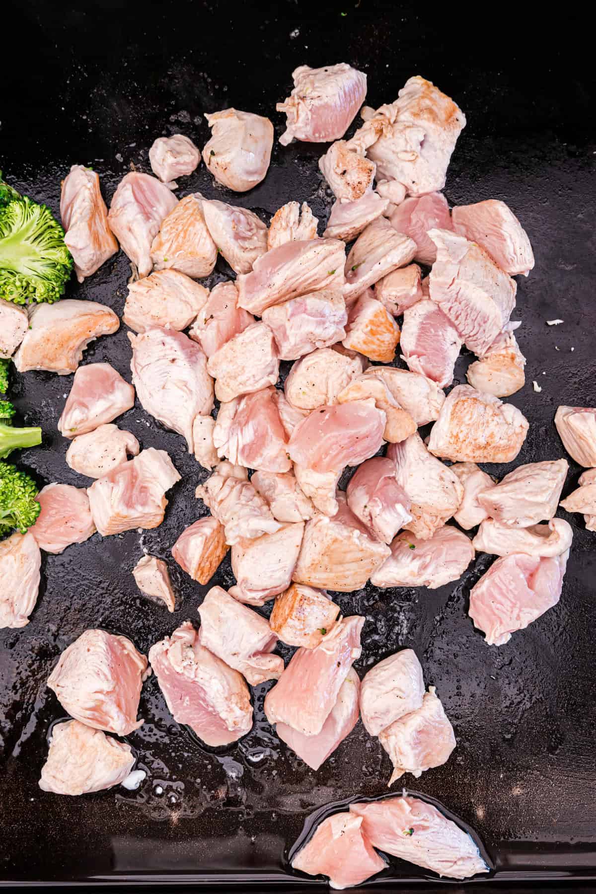 Cooked cubed chicken and broccoli florets on Blackstone griddle for Chicken Stir Fry