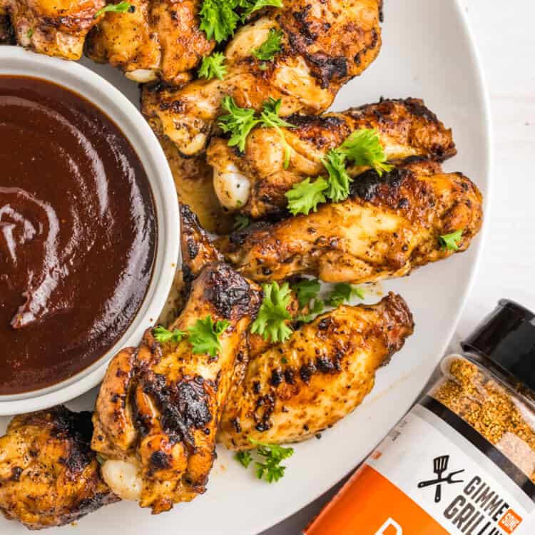 Blackstone Chicken Wings arranged on serving plate with BBQ dipping sauce in small bowl