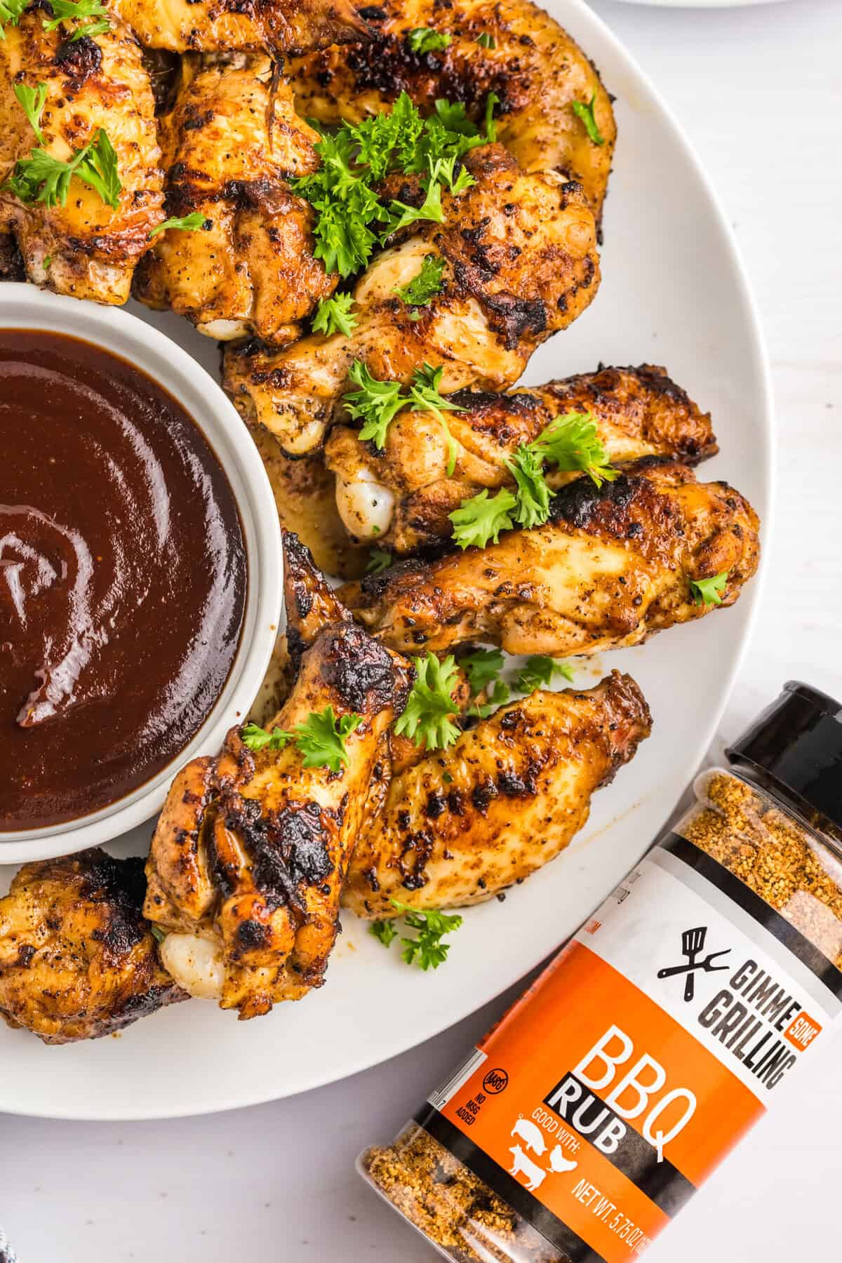 Blackstone Chicken Wings arranged on serving plate with BBQ dipping sauce in small bowl
