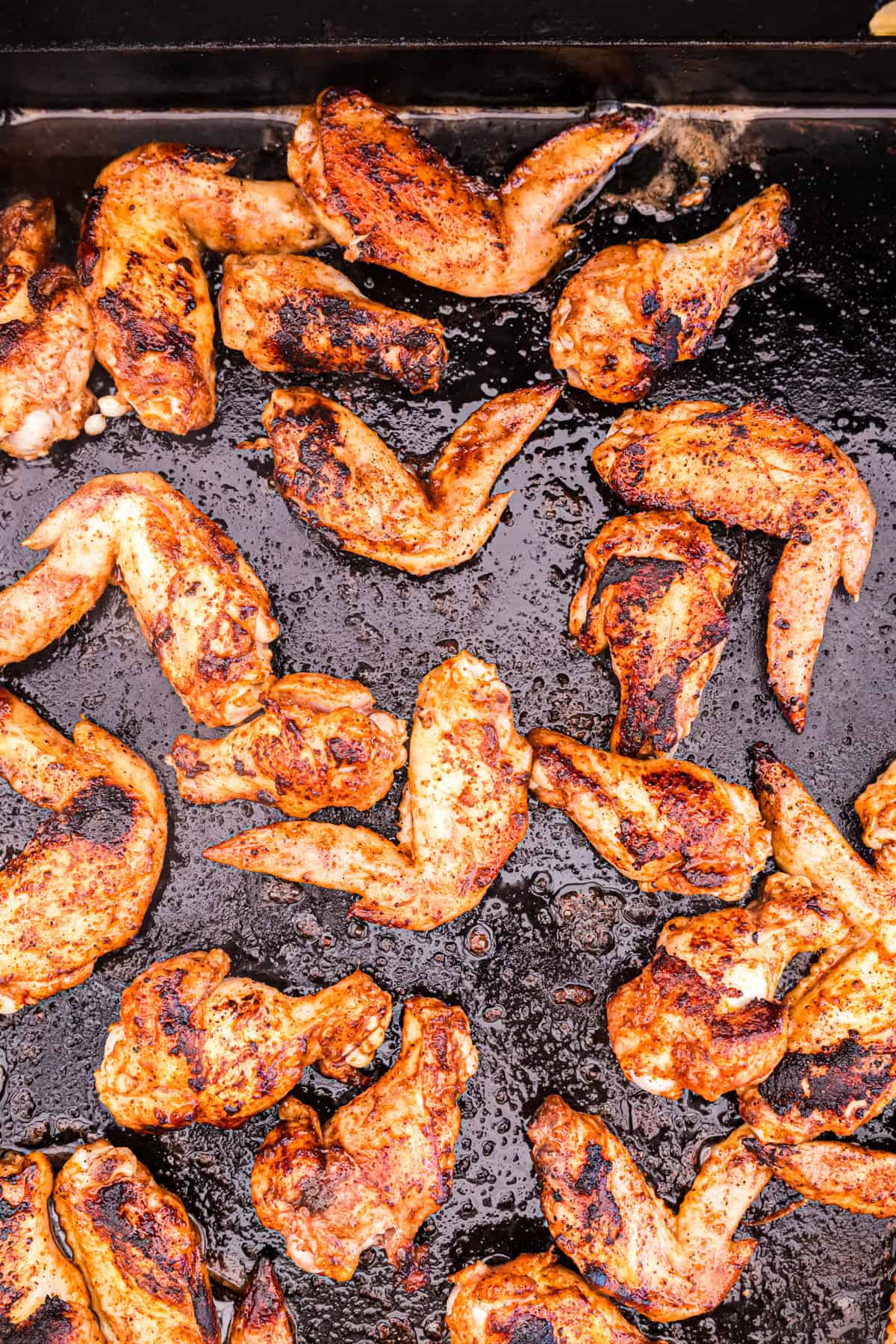 Flipped seasoned chicken wings on the griddle for Blackstone Chicken Wings recipe