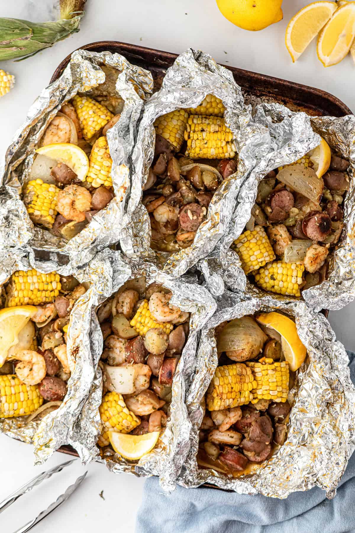 Shrimp Boil Foil Packets pulled open after grilling arranged on cooking sheet