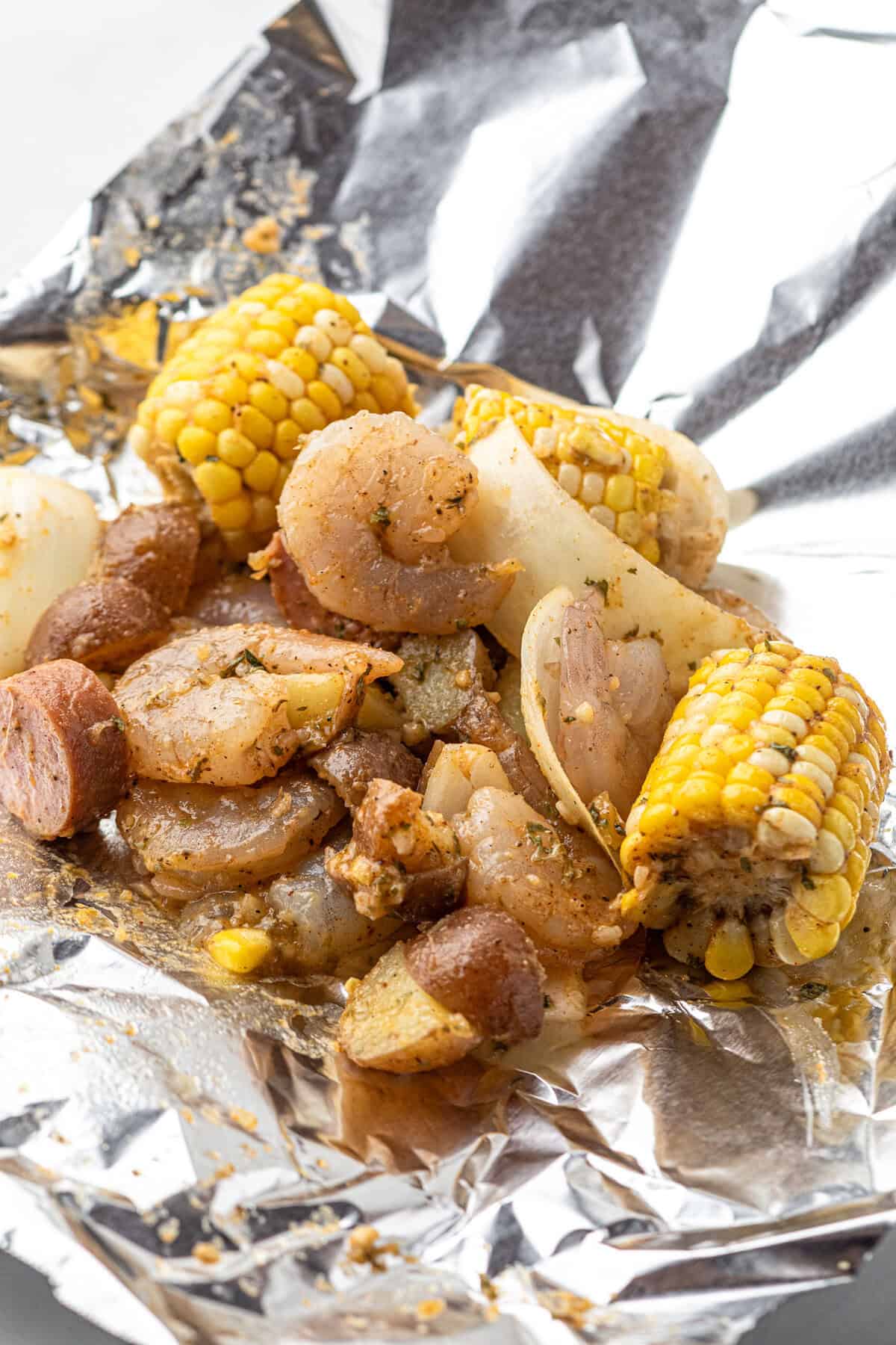 Scooping seasoned Shrimp Boil ingredients into foil for Shrimp Boil Foil Packets recipe