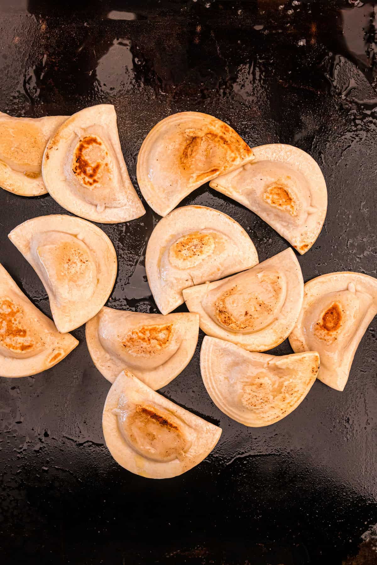 Browned pierogies on Blackstone griddle for Blackstone Sausage and Pierogies recipe