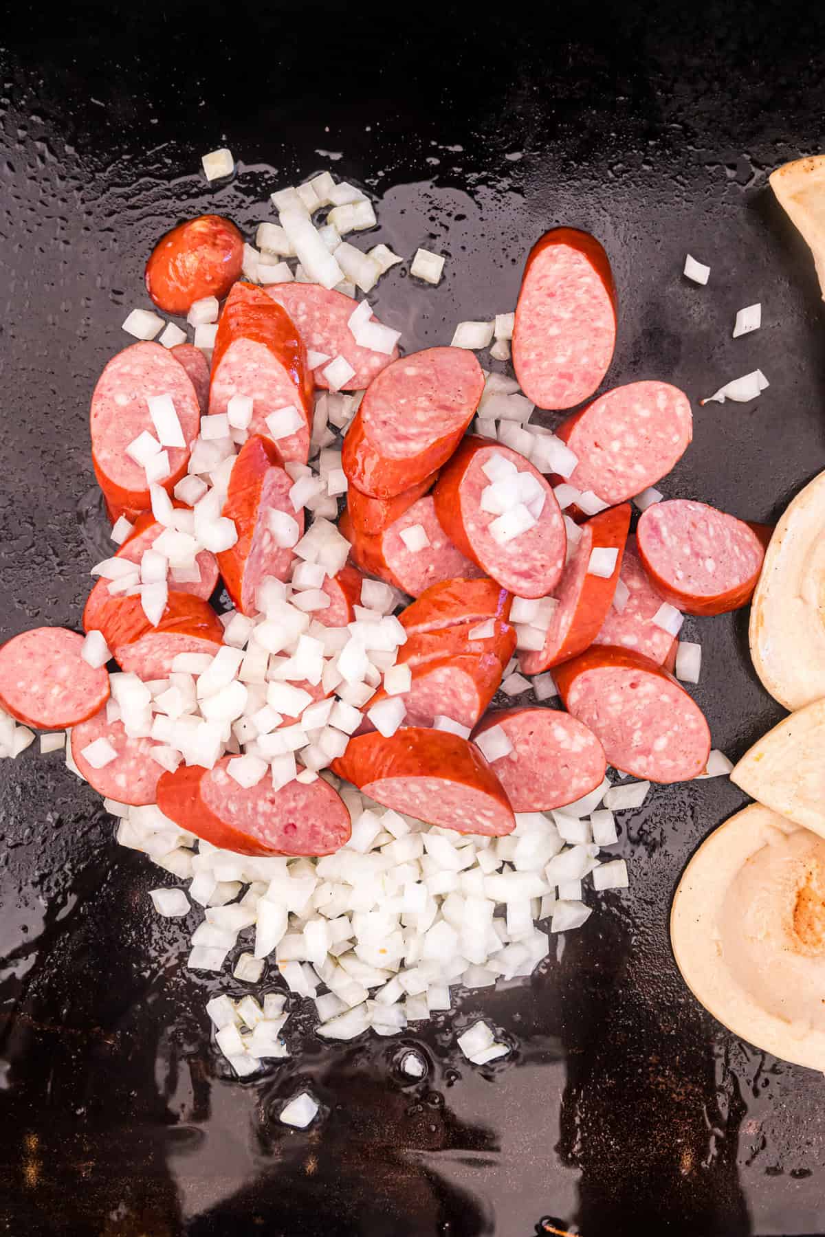 Cooking sliced sausage and diced onion on Blackstone for Blackstone Sausage and Pierogies
