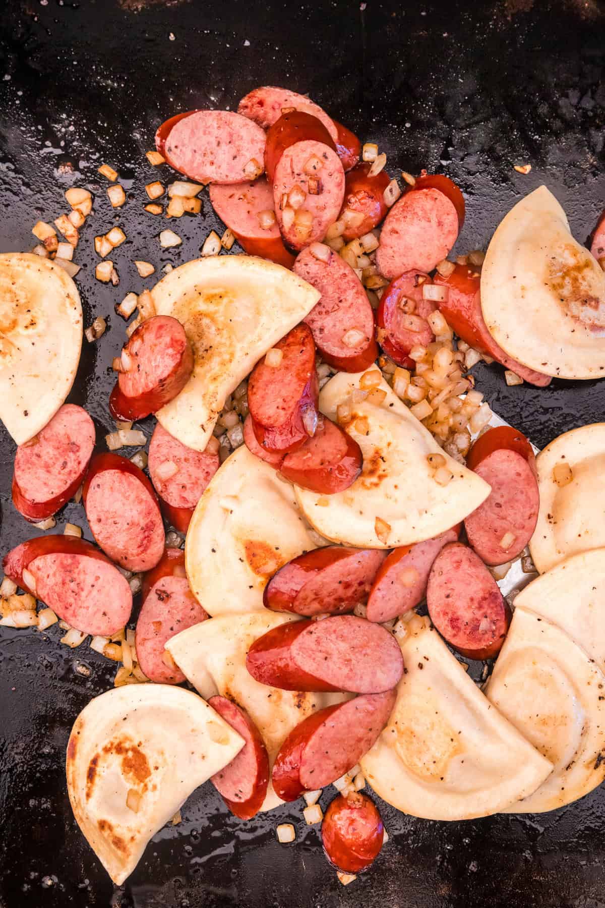 Tossing sausage, onion, and pierogies on the griddle for Blackstone Sausage and Pierogies