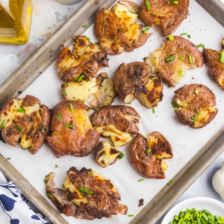 Blackstone Smashed Potatoes arranged on parchment lined baking sheet