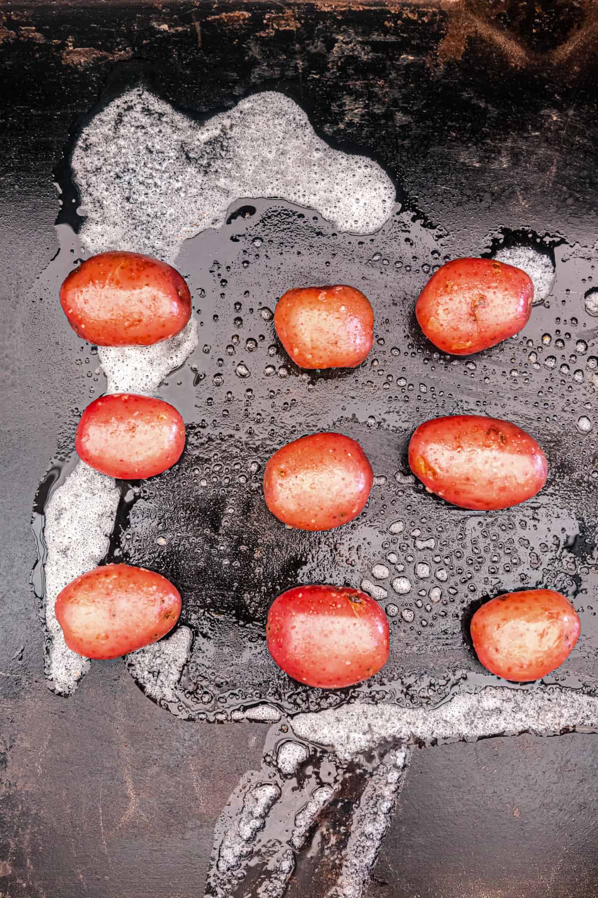 Seasoned boiled baby potatoes arranged on griddle for Blackstone Smashed Potatoes