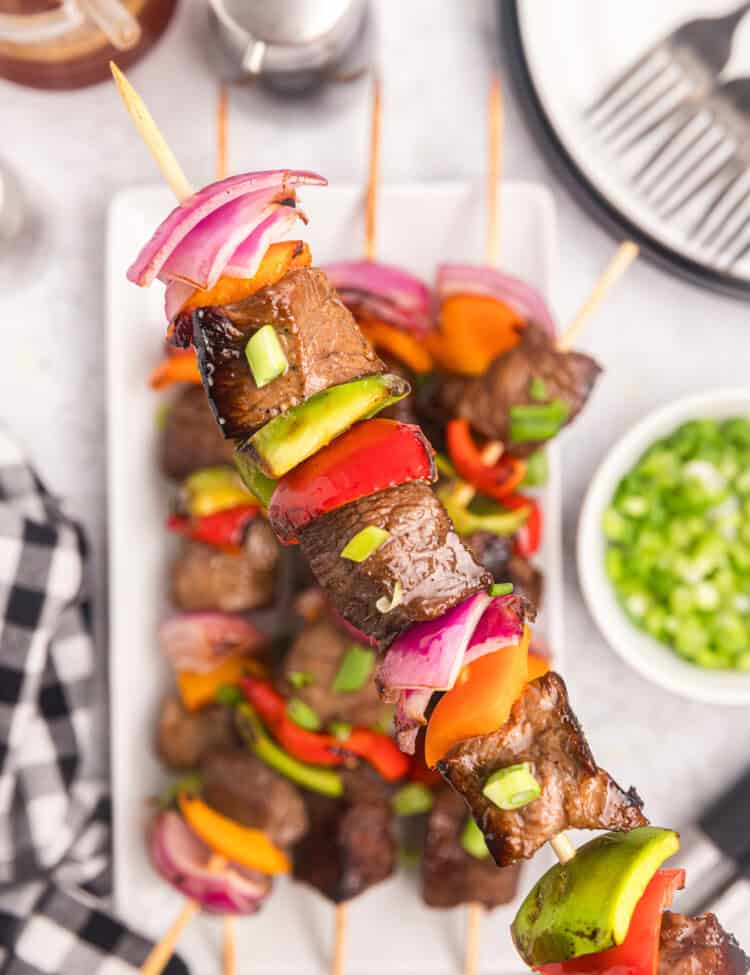 Blackstone Beef Kabobs arranged on serving plate, holding on kabob up close