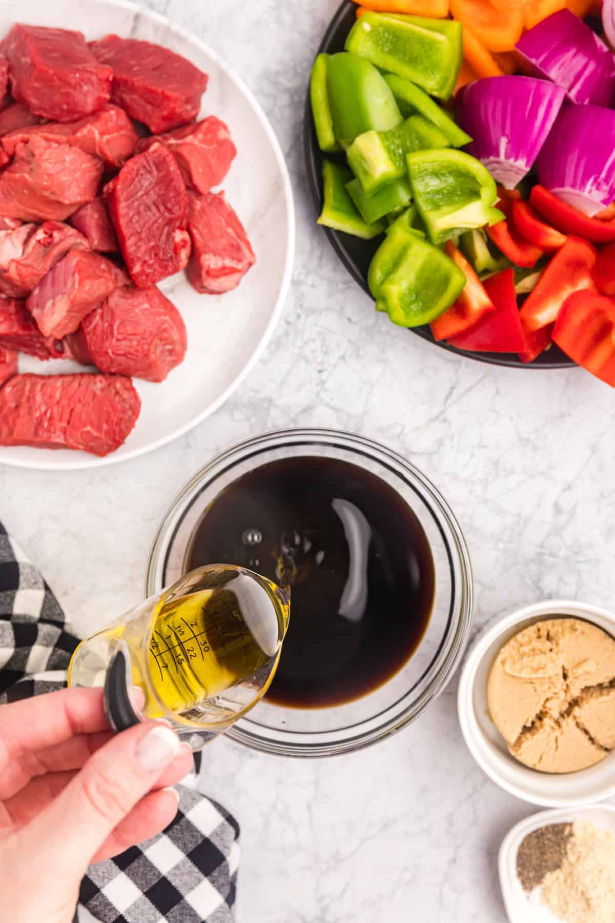 Pouring Blackstone Beef Kabobs marinade ingredients into small glass mixing bowl