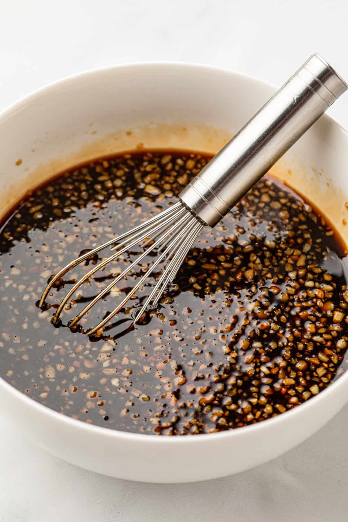 Whisking Grilled Honey Garlic Pork Chops marinade in white bowl