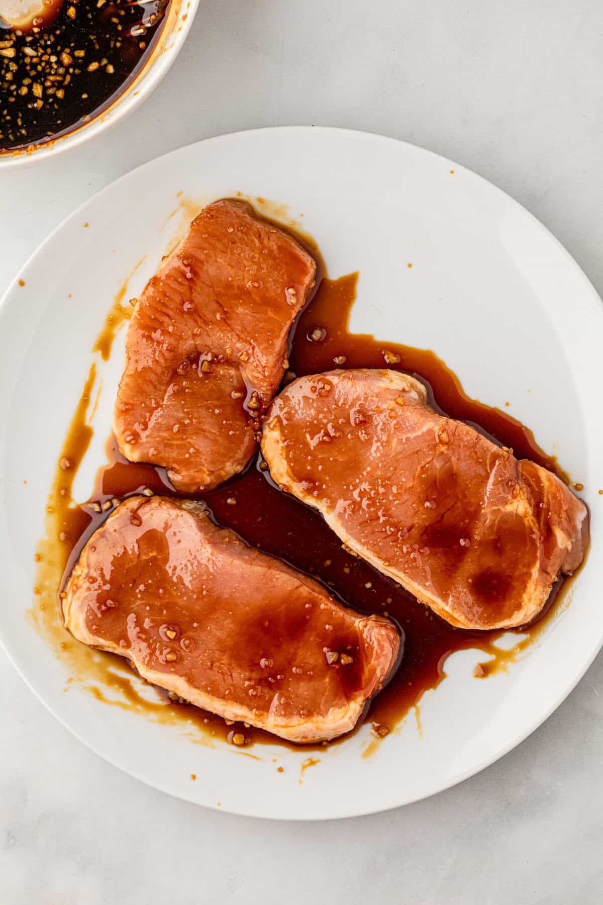 Grilled Honey Garlic Pork Chops in shallow bowl with marinade
