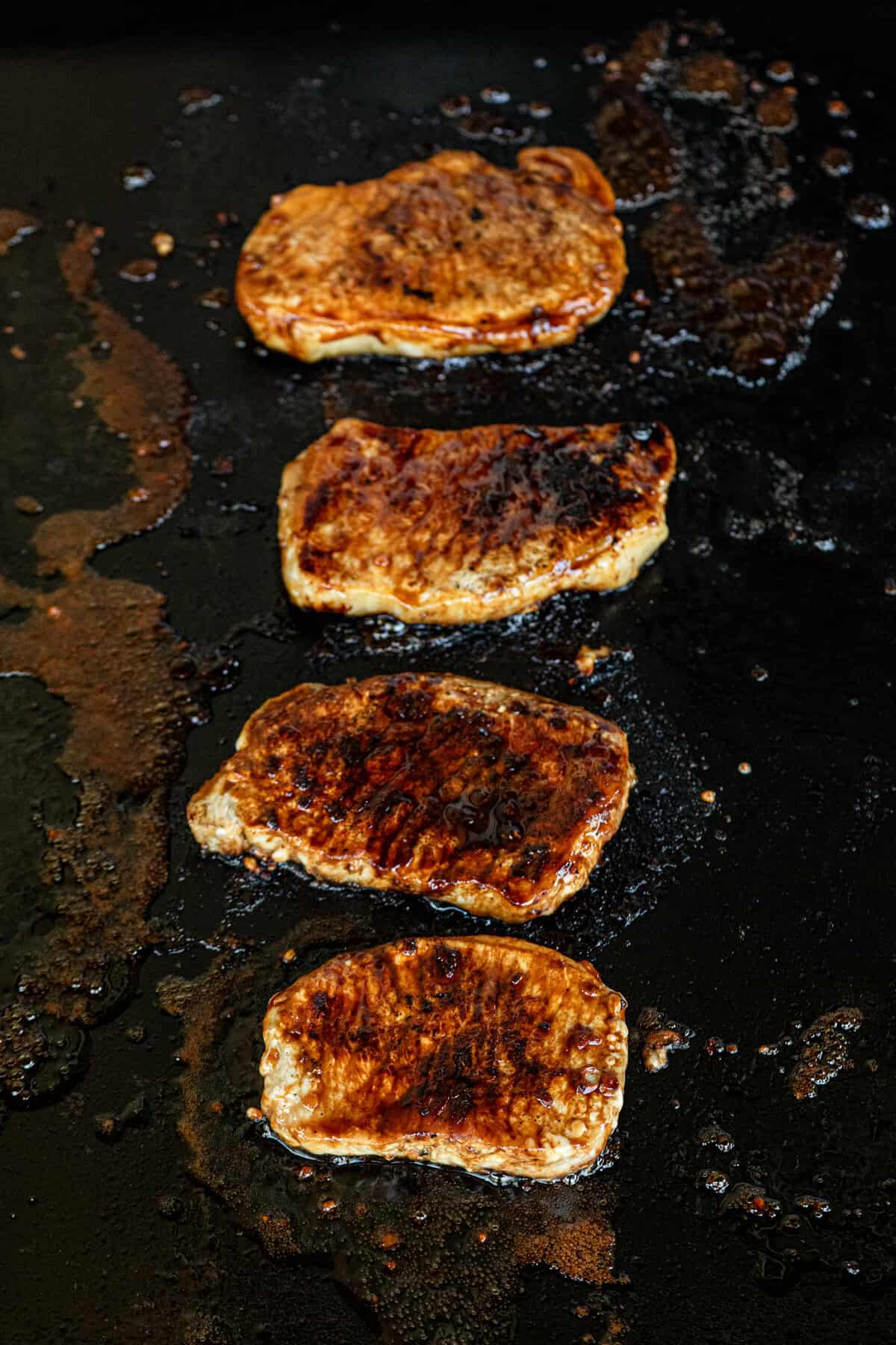 Grilled Honey Garlic Pork Chops on grill after being flipped