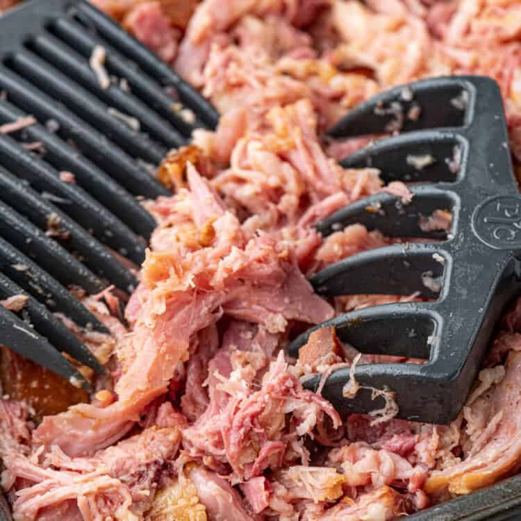 Pulled Pork Ham in cooking pan being pulled apart