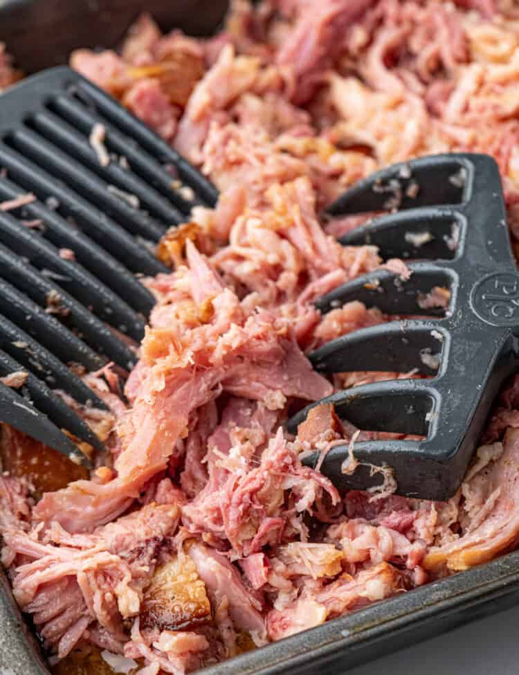 Pulled Pork Ham in cooking pan being pulled apart