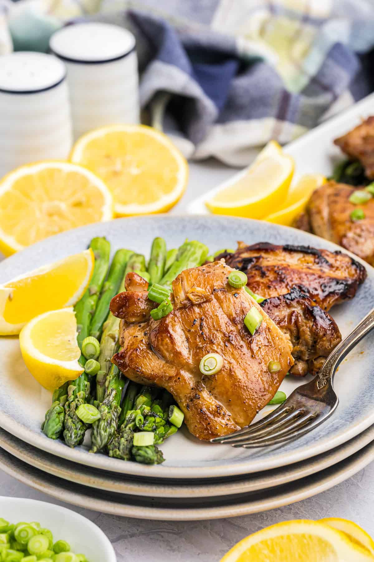 Blackstone Chicken Thighs on dinner plate with side of asparagus and fresh lemon