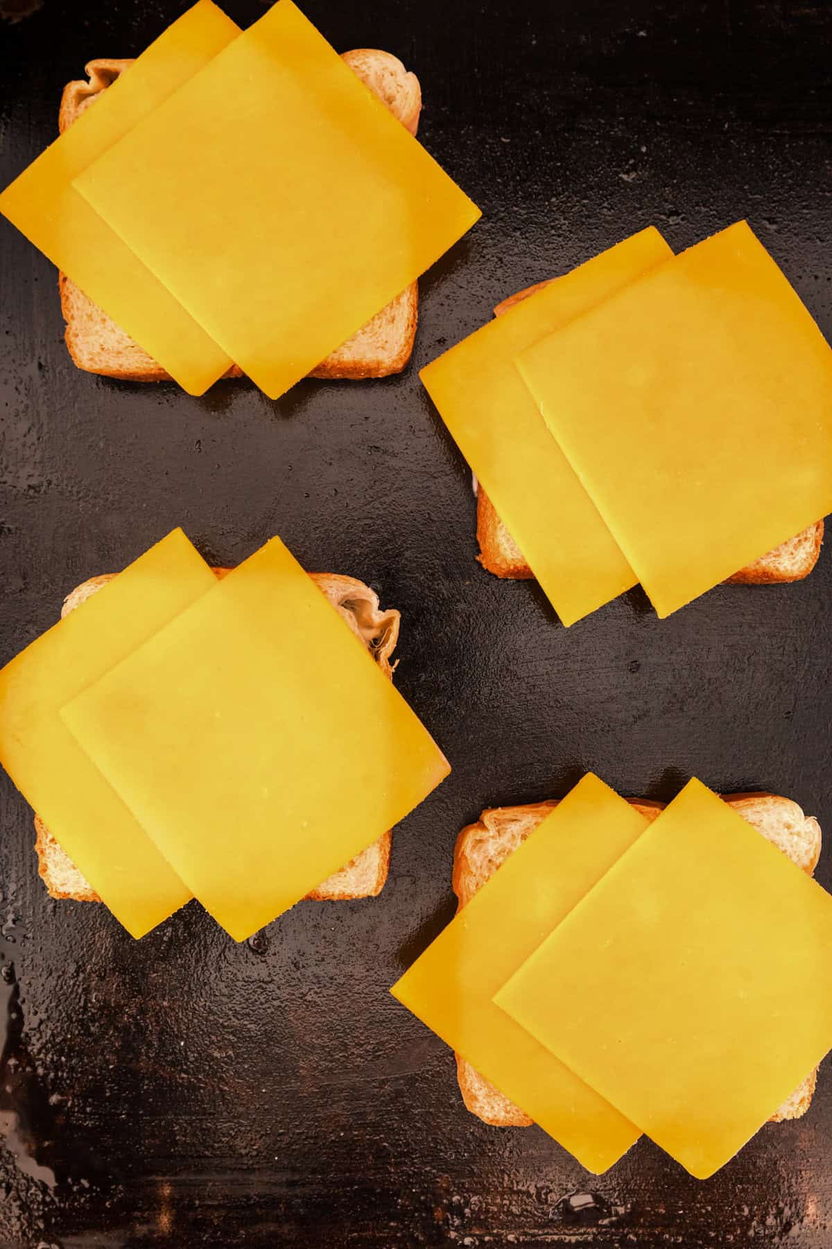 Adding two slices of cheddar cheese to bread on griddle for Blackstone Grilled Cheese