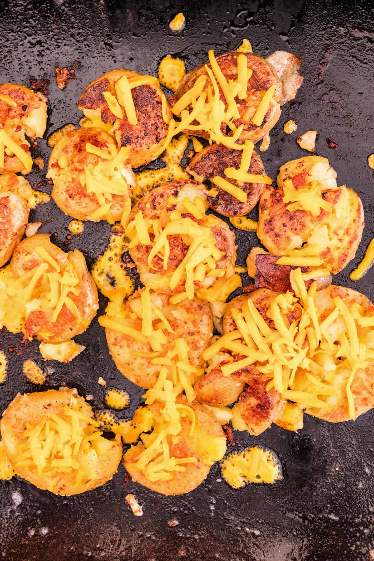 Adding shredded cheese to Blackstone Loaded Smashed Potatoes