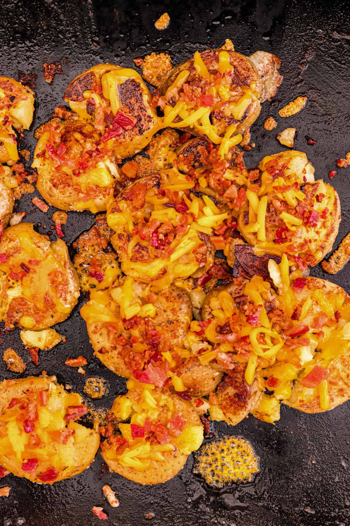 Blackstone Loaded Smashed Potatoes topped with shredded cheese