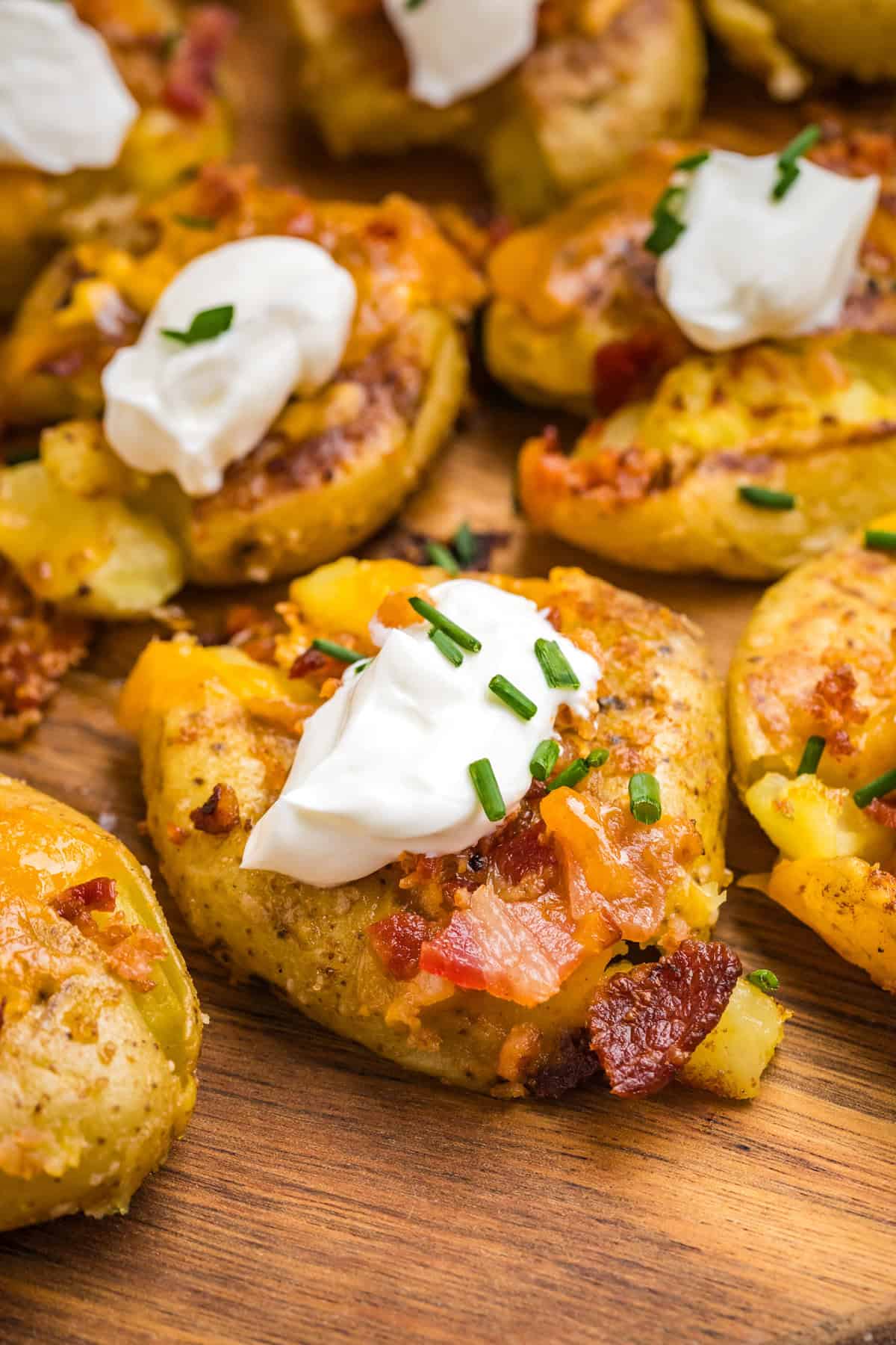 Topping the Blackstone Loaded Smashed Potatoes with sour cream and fresh chopped chives