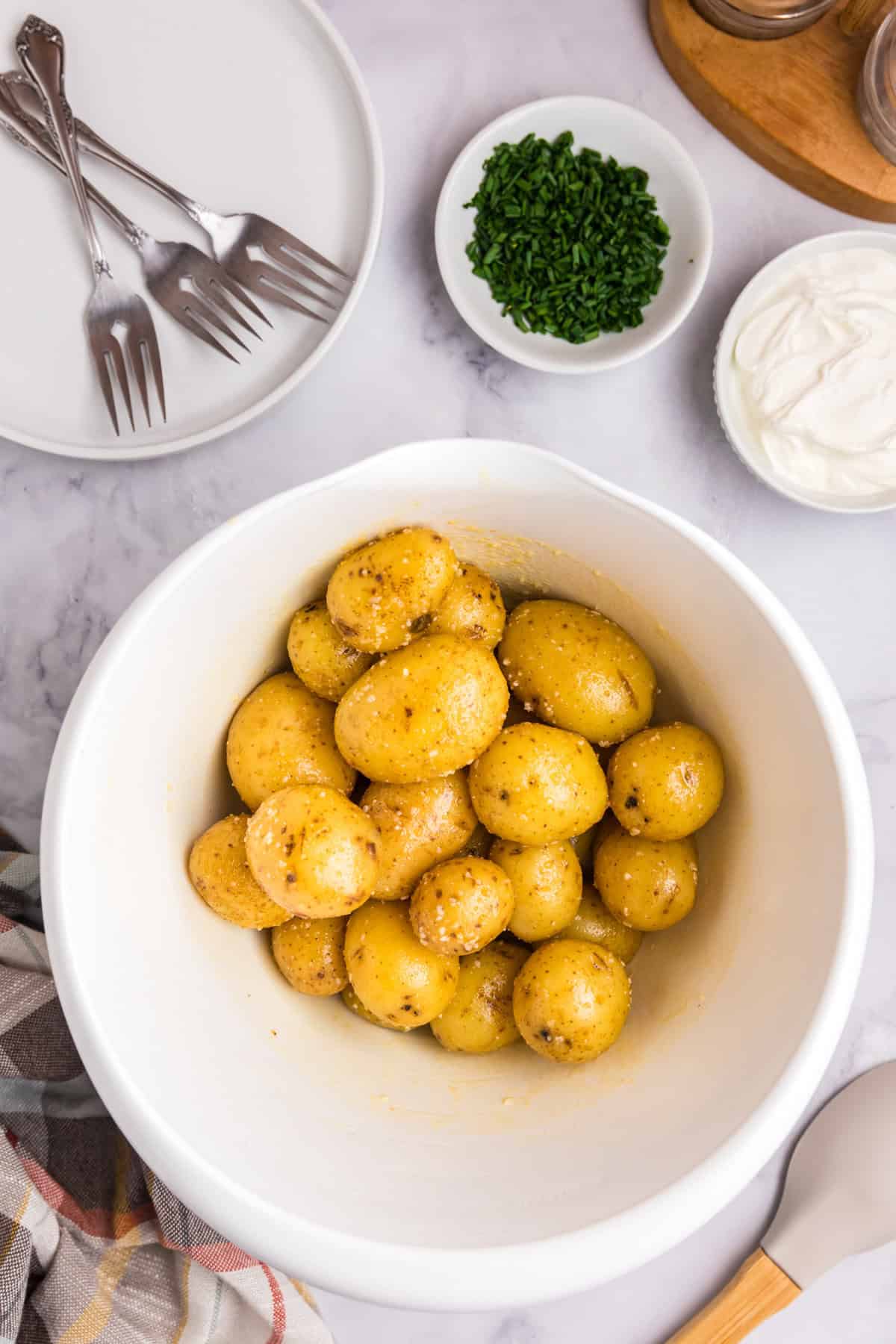 Tossed cooked potatoes with seasoning in large mixing bowl for Blackstone Loaded Smashed Potatoes recipe