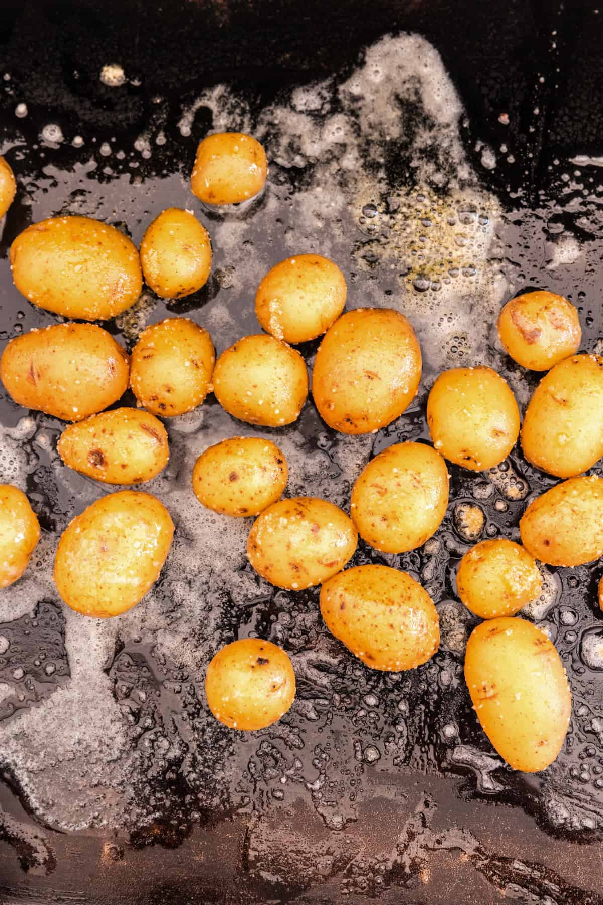 Seasoned cooked potatoes on Blackstone griddle for Loaded Smashed Potatoes recipe