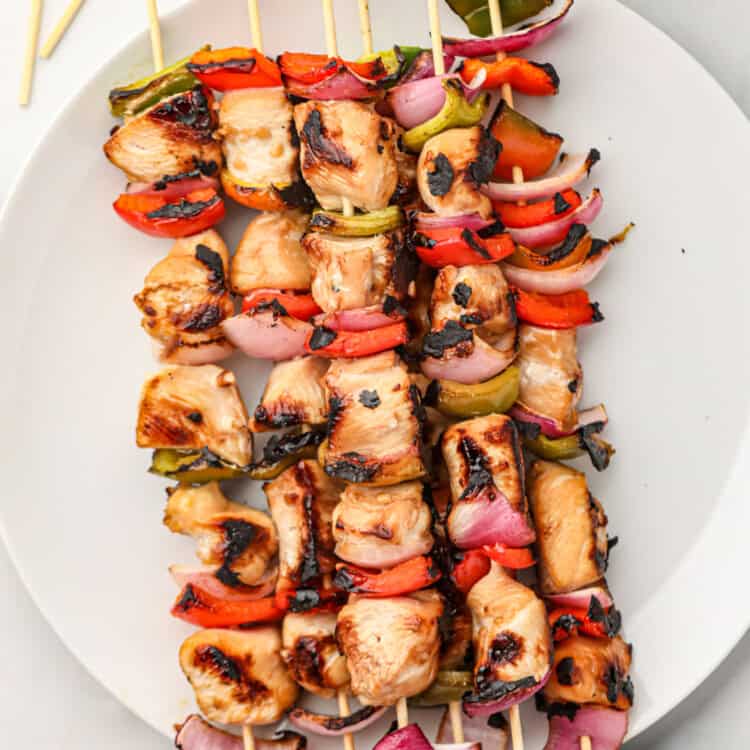 Chicken Teriyaki Skewers stacked and arranged on white serving plate