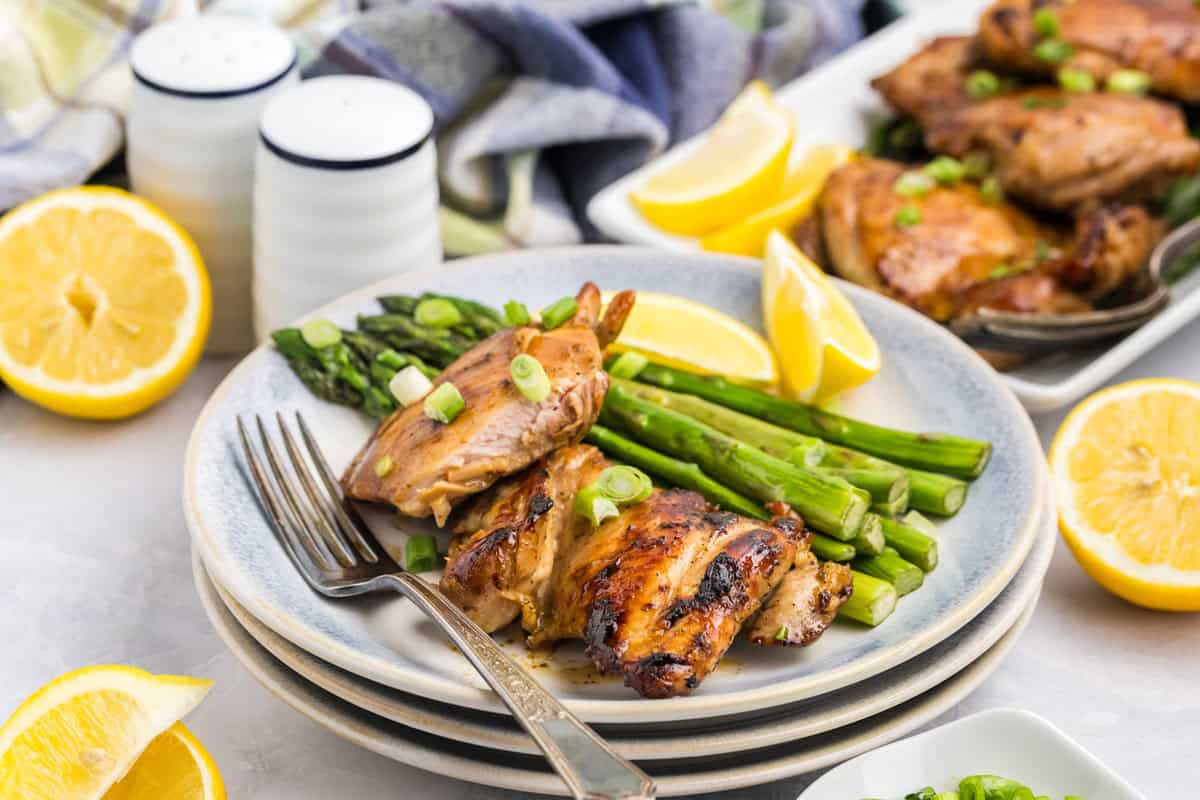 Blackstone Chicken Thighs on dinner plate with side of asparagus and fresh lemon