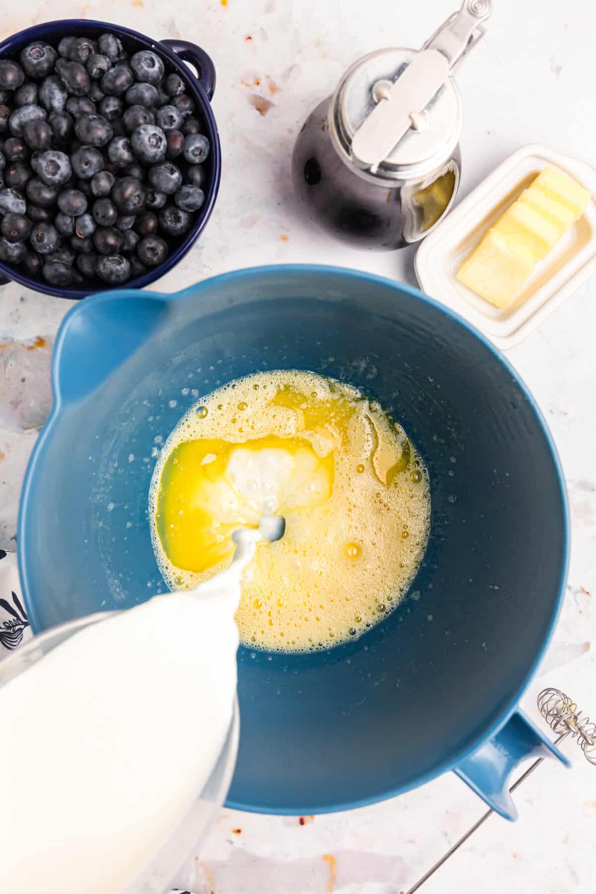 Adding buttermilk to melted butter mixture in bowl for Blackstone Buttermilk Pancakes