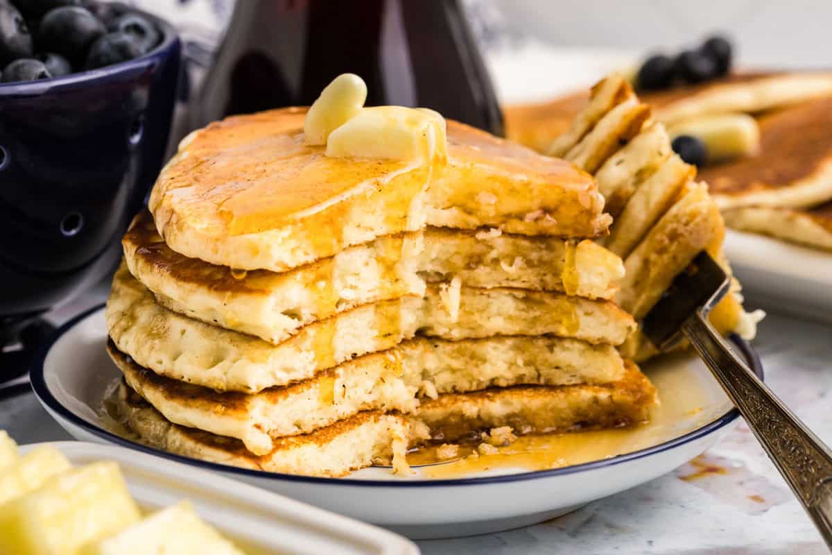 Cut stack of Blackstone Buttermilk Pancakes with butter and syrup on plate